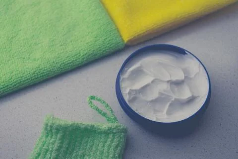 Opened round container with white cream on a table with towels. 스톡 사진