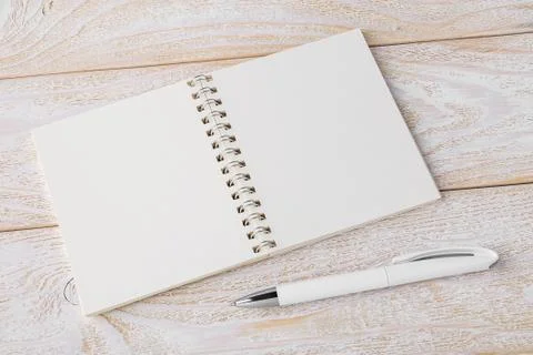 Opened spring notepad and white ballpoint pen on a white wood table. Foto stock