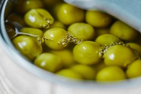 Opened tin with boiled green peas on a white background Stock Photos