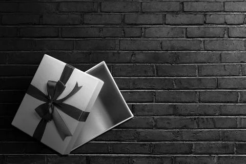 Opened a white gift box with a black ribbon with a black wall background Stock Photos