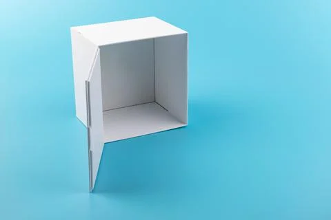 Opened white paper cube box on a blue background. Stock Photos