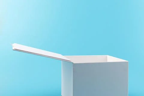 Opened white paper cube box on a blue background. Stock Photos