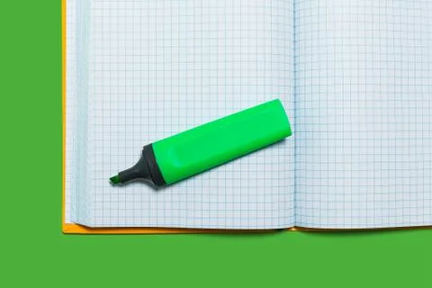 Opened workbook and a marker on a green surface Stock Photos