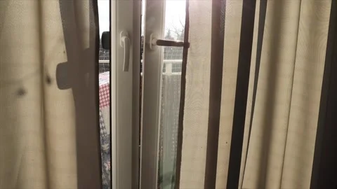 Opening balcony door for ventilation, sunlight filtering through curtains, home Vidéo 303850411