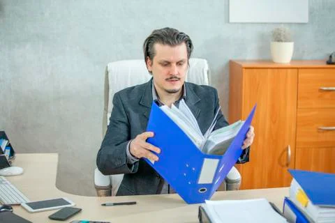 Opening a big blue folder to check something Stock Photos
