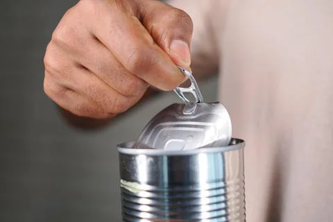 Opening a can in a kitchen setting using a hand with a pull tab Stock Photos