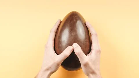 Opening a chocolate easter egg on yellow background Stock Photos