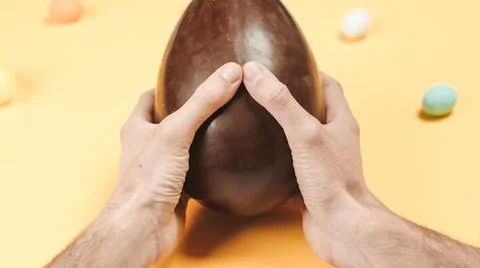 Opening a chocolate easter egg on yellow background Stock Photos