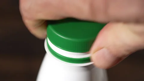 Opening the cork on a white plastic bottle with milk product by hand Stock Footage 305328799