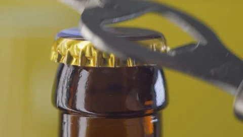 Opening drink dark bottle with bottle opener on yellow background Stock Footage 144554492