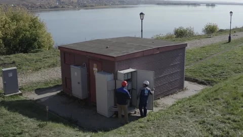Opening the electric meter cabinet next to the river. View from the copter. Stock Footage 167250797