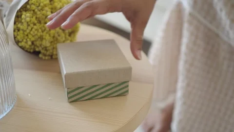Opening a gift box on a wooden table with flowers nearby Stock Footage 340941217