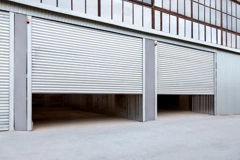 Opening gray iron shutter door of garage and industrial building warehouse. Stock Photos