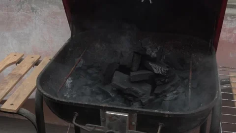 Opening a grill and dumping all its smoke from the coal heating up inside on the Stock Footage 160087630