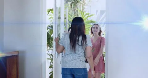 Opening host wearing patterned top, jeans greeting visitor in pink dress at Stock Photos