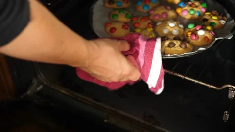 Opening oven taking tray full of cookies with colorful chocolate candy Stock Footage 135241334