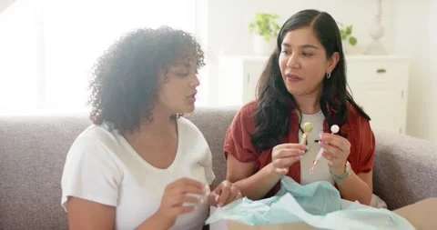 Opening package, two women wearing rust shirt and white tee comparing decorative Stock Footage 336658662