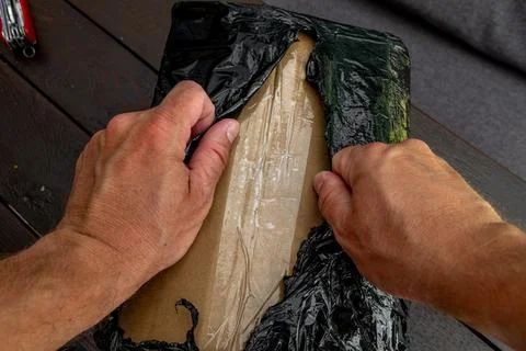 Opening a package wrapped in black stretch with a penknife, Stock Photos