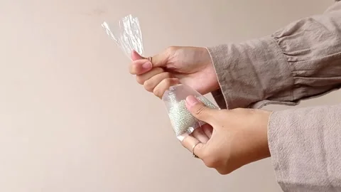 Opening a plastic of white pearls Stock Footage 146257358