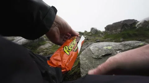 Opening Reese's peanut butter cups chocolates outdoors Stock Footage 138163111