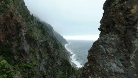 Opening scene moving between rocks discovering overcast ocean view Video stock 113325042