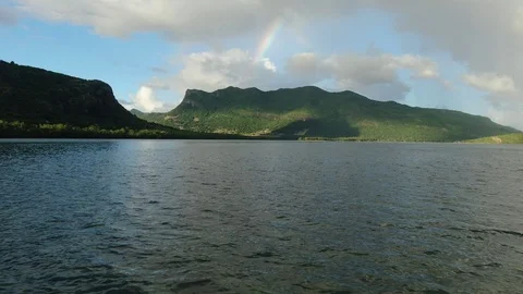 Opening scene moving over ocean surface with a rainbow over mountain Video stock 120427009