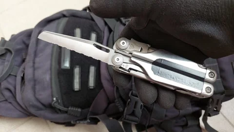 Opening serrated knife blade on heavy duty multitool, top view close up Stock Footage 346363966