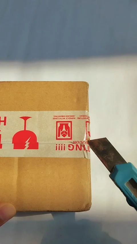 Opening the side of a cardboard package using a cutter knife. Hands cutting.. Vídeos de archivo 330749258