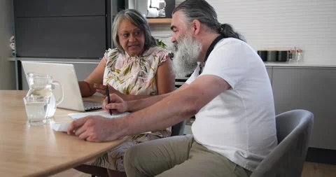 Opening spreadsheet on laptop at kitchen table, senior couple pointing figures Stock Footage 336608959