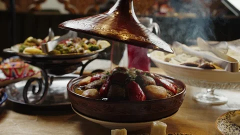 Opening a steaming tagine pot at a festive table Stock Footage 302088417