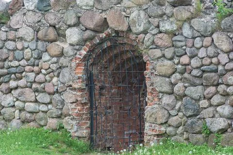 Opening in the stone wall is closed with a latticework Stock Photos