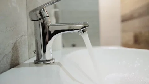 Opening the tap with water in the bathroom, close-up. The concept of payment for Stock Footage 243161535