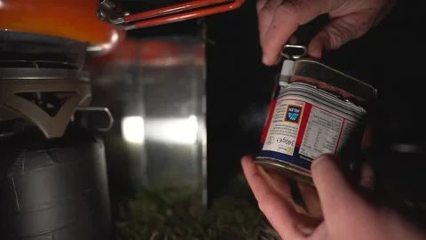 Opening a tin of Aldi corned beef at night while camping Stock Footage 283555579