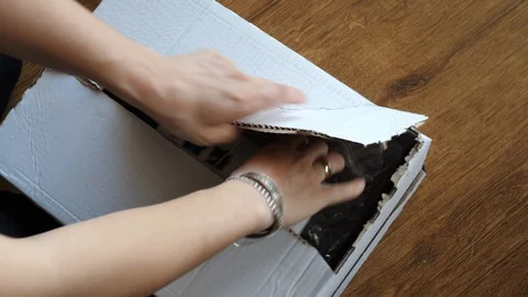 Opening unpacking small item in bog box wasting place Stock Footage 129100486