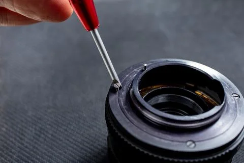 Opening a vintage camera lens, screw driver and tiny screws, selective focu.. Stock Photos