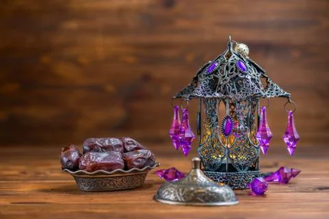 Openwork arabian lamp with plate of dates over wooden background, Ramadan Kar Foto stock