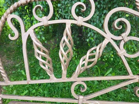 Openwork bronze-colored wrought-iron elements against a background of green Foto stock