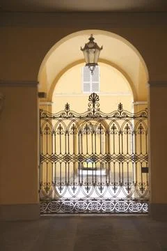 Openwork metal gate between the walls of the houses under the arch Stock Photos