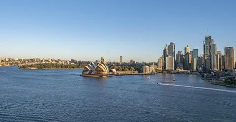 Opera House and cityscape captured from water, with boats and clear sky Stock Photos