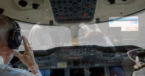 Operating flight deck in corporate jet cabin, two uniformed pilots using Foto stock