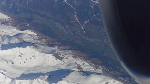 Operating jet engine of the airplane, snowy montain peaks and distant alpine Stock Photos