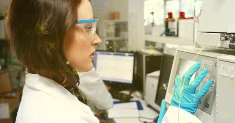Operating lab tech using instrument keypad tubing at lab bench wearing coat Stock Photos