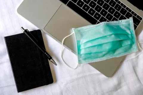 Operating room mask on a laptop computer along with a notebook and a pen. Foto stock