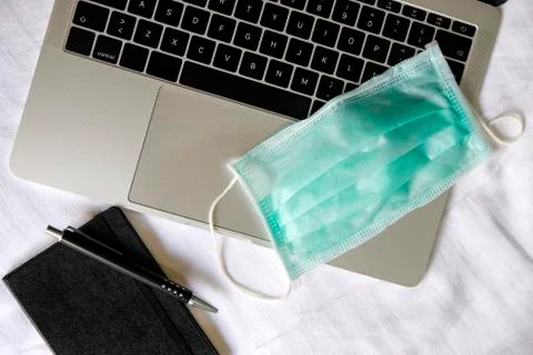 Operating room mask on a laptop computer along with a notebook and a pen. Foto stock