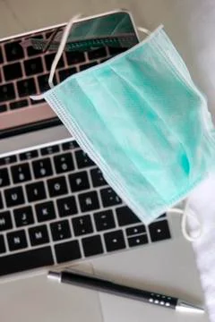 Operating room mask on a laptop computer and a pen. Stock Photos