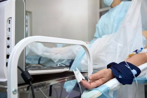 Operating room with a patient lying on a table connected to medical devices Stock Photos