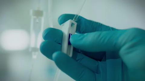 Operating room. The procedure in protective gloves slowly sets up iv drip in Stock Footage 262278057