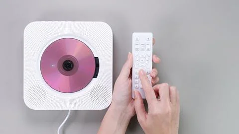 Operating a Wall-Mounted CD Player with Remote Control. Modern Music Listening. Stock Photos