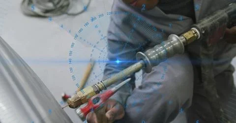 Operating welder in gray coveralls cutting curved pipe in workshop with torch Stock Photos