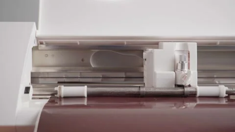 Operation of a compact cutting plotter cutting brown vinyl film Stock Footage 166288348